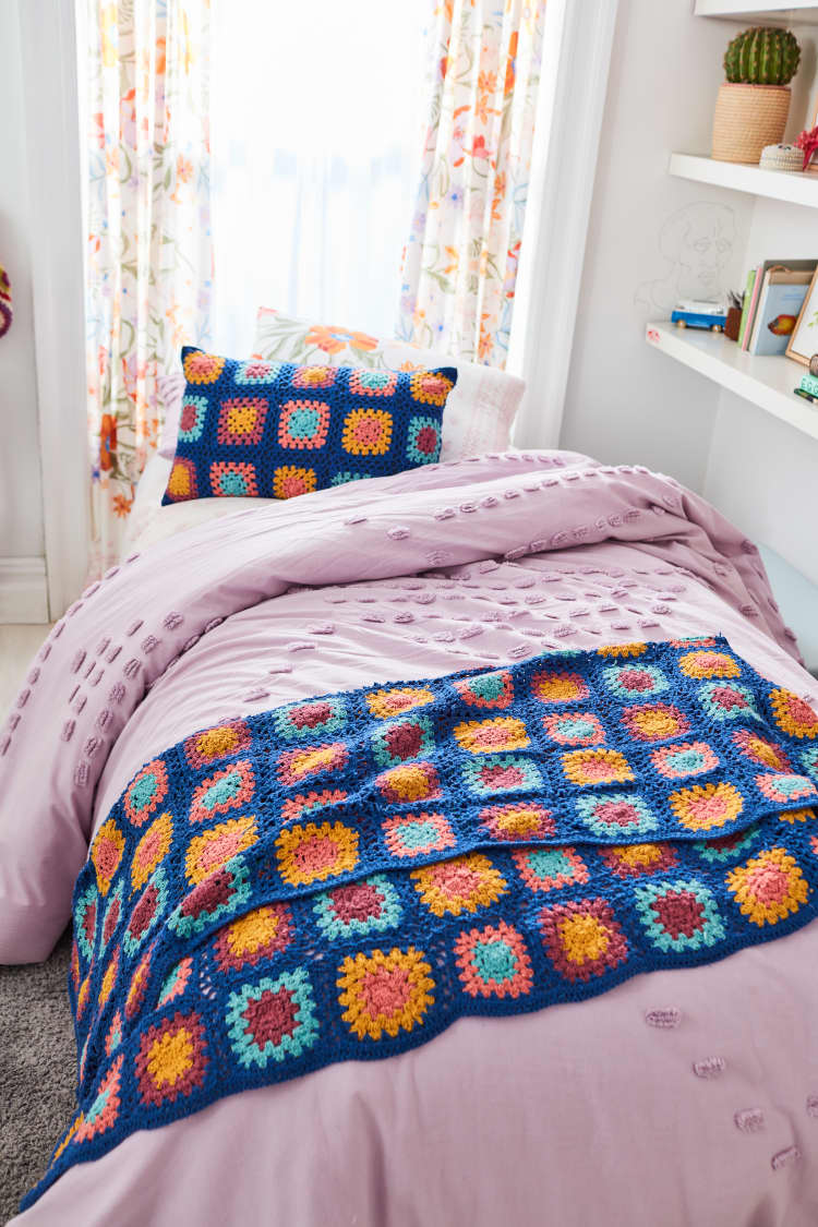 Boho style bedroom with pink duvet and knitted afghan