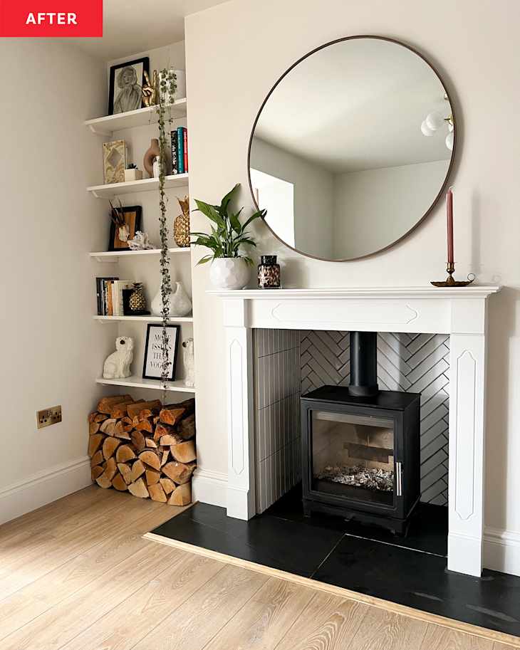 Renovated white living room with cast iron fireplace with mirror hanging over the mantel and built-in bookshelves