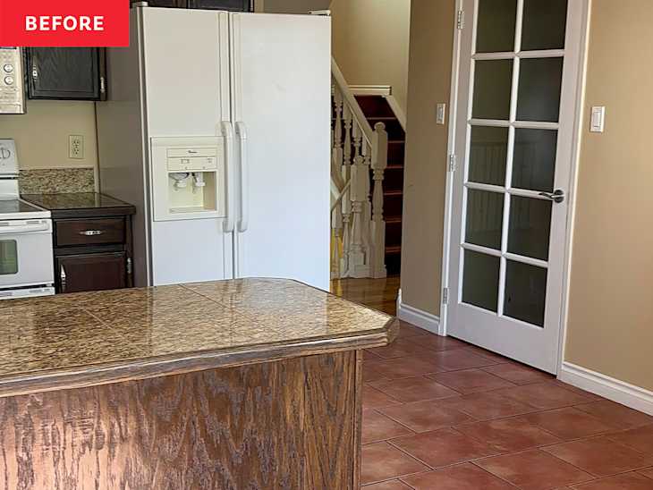 Kitchen with a granite countertop island, white refrigerator, and a glass-paneled door leading to stairs.