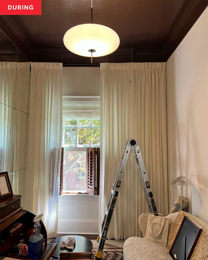 Cozy room with a beige sofa, a ladder, sheer curtains, and a modern ceiling light above a window.